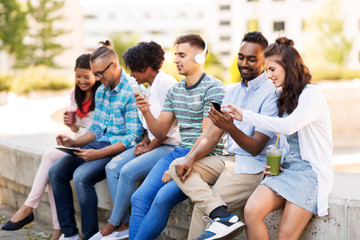 technology, friendship and international concept - group of friends with smartphones hanging out in summer city
