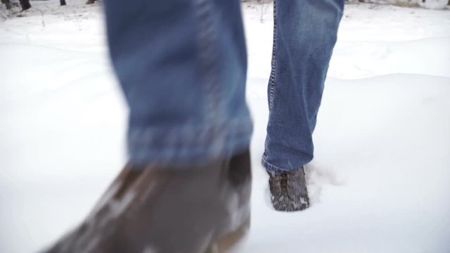 Close-up of man's feet walking on the mountains in the snow. Slow-motion filming