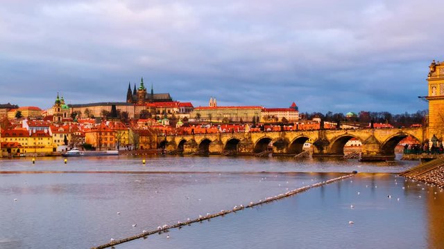 Prague, Czech Republic. Charles Bridge over Vltava river in Prague, Czech Republic. Timelapse during the sunset with touristic boats and Old Town Bridge Tower. Cloudy sky, day to night time-lapse, pan