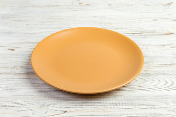 Perspective view. Empty yellow matte plate on white wooden background