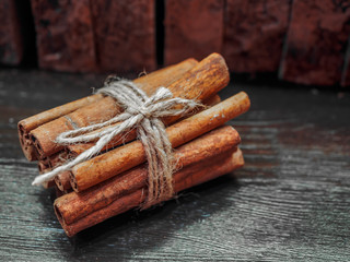 Three cinnamon sticks tied with jute rope on a black wooden table
