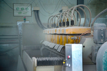 Big old machine in the shop. Dust in the air. Row of cylinders on the frame.