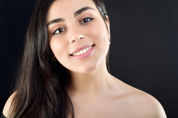 Obraz premium Portrait of a beautiful girl on a black background which is naked on the shoulders