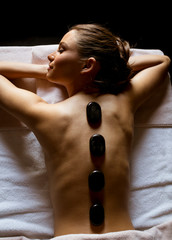 Obraz na płótnie Canvas Young woman having a hot stone massage therapy
