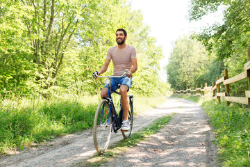 people, leisure and lifestyle - happy man riding fixie bicycle at summer park