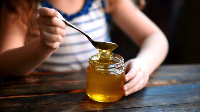 Bank with honey in the hands of a child
