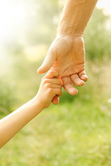 hands of parent and child in nature