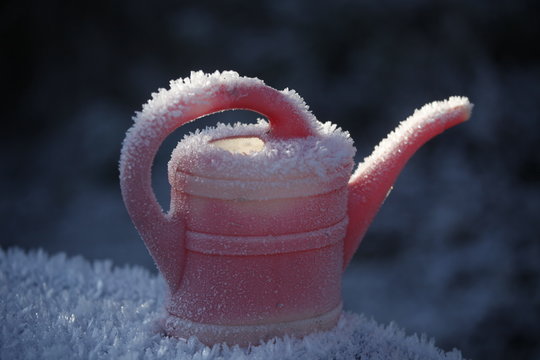 Rote Gie&szlig;kanne im Winter mit Eis, Schnee und Frost