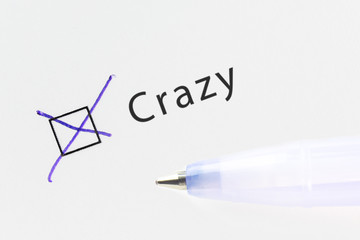 Crazy - checkbox with a cross on white paper with blue pen. Checklist concept.
