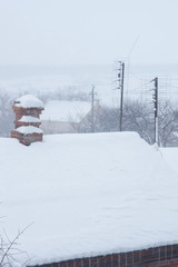 Rural roof in winter day.  Chimney in red bricks with white snow 