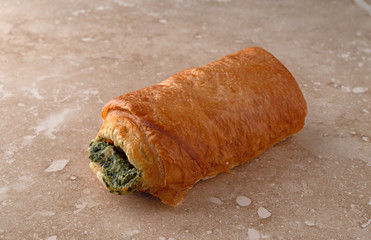 Pastry with a spinach filling on a marble counter top side view.
