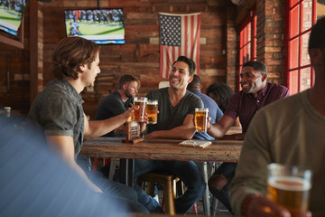 Group Of Male Friends Meeting And Drinking Beer In Sports Bar Together