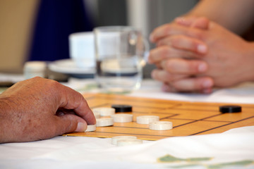 Senioren Hände spielen Brettspiel Mühle.