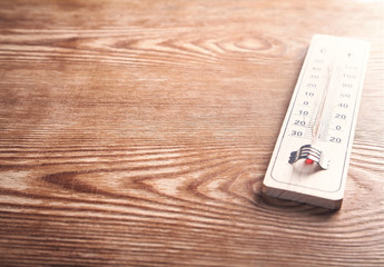 Wooden thermometer on wooden background.