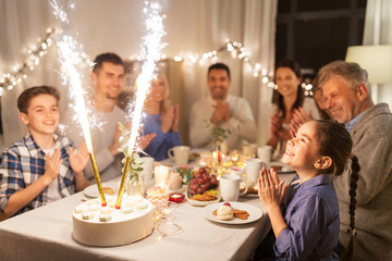 celebration, birthday and people concept - happy family having dinner party with fountain fireworks or sparkler candles burning on cake at home