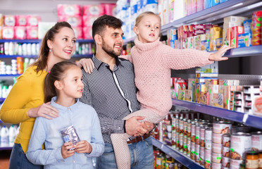 Happy family with two little girls buying food products in supermarket