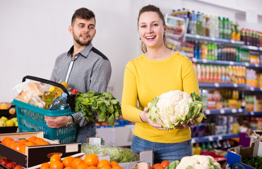 Glad woman with husband looking for vegetables