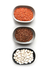 Fototapeta premium Collection of different groats isolated on black background. Top view of chickpeas, buckwheat, beans in bowls.