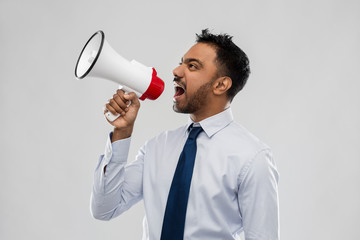 business, stress and people concept - indian businessman screaming to loudspeaker over grey...