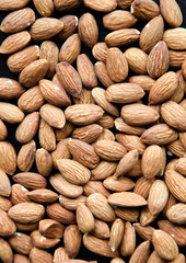 Natural background made in nuts. Black and stone background with almonds.