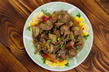 Stewed chicken liver with apple and onion on wooden table
