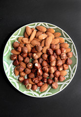 Very delicious nuts. Walnuts and almonds bowl on black background.