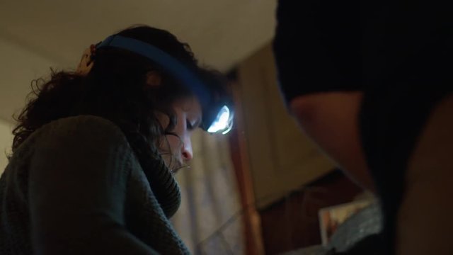 Young woman in head-strap lamp helps prepare a fireplace out of frame