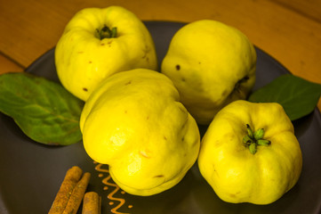large yellow quince fruits on a ceramic plate, with anise, cinnamon, and walnuts