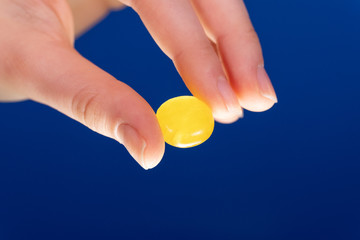 Hand gibt gelbe Pastille