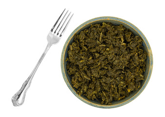 Bowl of chopped kale with a fork to the side on a white background.