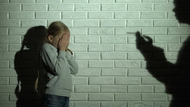 Frightened kid covering eyes, parent shadow smoking cigarette, drug addiction