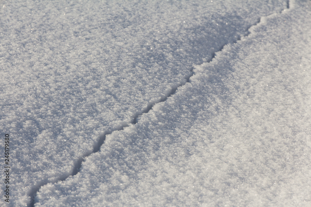 Wall mural long winding crack in clear deep snow