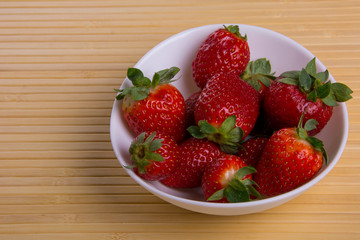 Strawberry in white plate close-up on light background 2