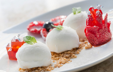 three white icecream balls with berries on white dish