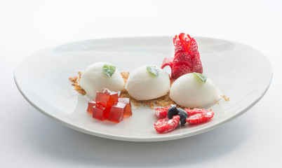 three white icecream balls with berries on white dish