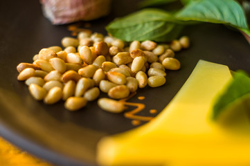 Fresh ingredients for preparing Italian pesto sauce - lemon basil sprigs, peeled seeds of cedar nuts, large garlic clove, Greek olive oil, Parmesan cheese