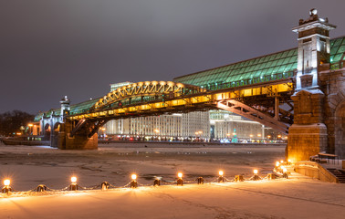 a beautiful bridge illuminated by a multitude of illuminations against the backdrop of a night river in winter