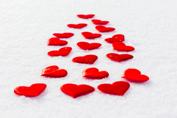 Red hearts on glittering snow. Vilentine's day theme.