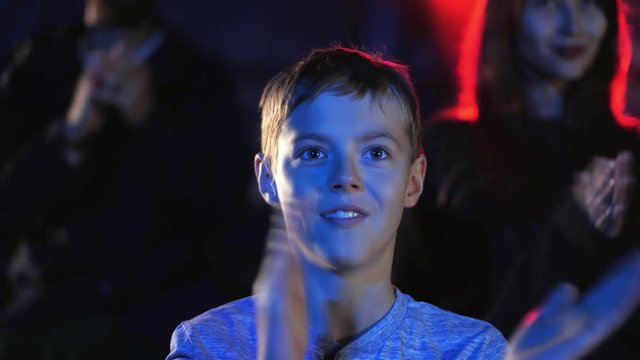Surprised boy clap hands in circus to the acrobatic and magic show artists