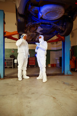 Crime investigation - collecting of evidences and traces from chassis of suspected car in police garage under UV light