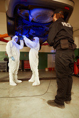 Crime investigation - collecting of evidences and traces from chassis of suspected car in police garage under UV light