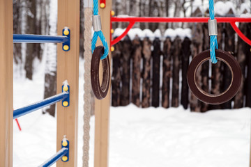 Gymnastic rings close-up on a children's playground in the winter, beautiful background.