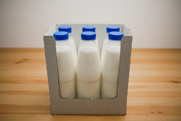 milk bottles in cardboard box on wooden table