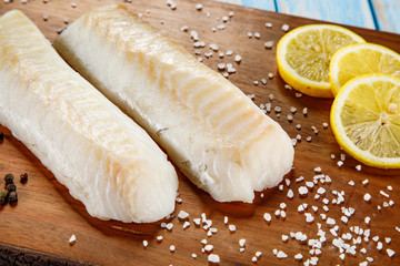 Fresh raw cod served on cutting board on wooden table