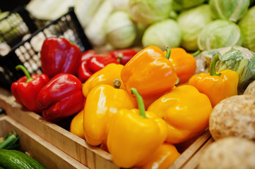 Colorful shiny fresh vegetables. Bell sweet yellow and red peppers on the shelf of a supermarket or grocery store.