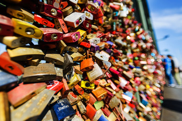 Fototapeta na wymiar Love locks on a bridge, people in bokeh on background