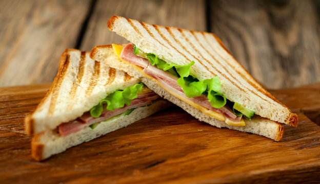 Two sandwiches on a cutting board on a wooden background in a rustic style. 