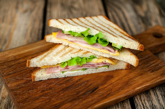 Two sandwiches on a cutting board on a wooden background in a rustic style. 