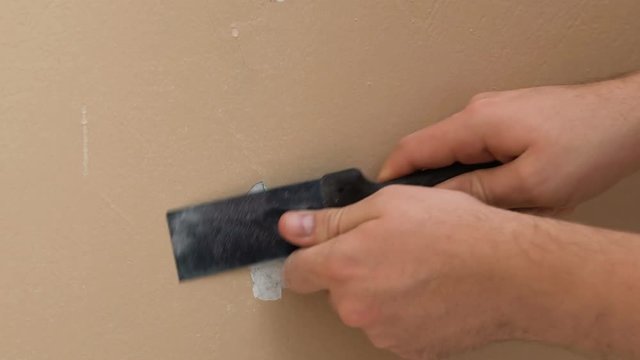 Close up of man's hand peeling a paint on an old house wall