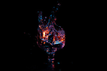 Colorful water being poured into glass isolated on a black background